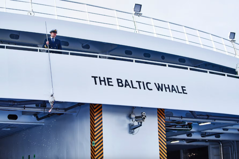 A man stood on the deck of a large ferry bearing the name THE BALTIC WHALE