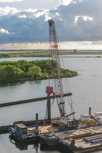 Liebherr LR 1130.1 unplugged crawler crane on a pontoon using a vibrator to install sheet piles at the Brouwer sluice